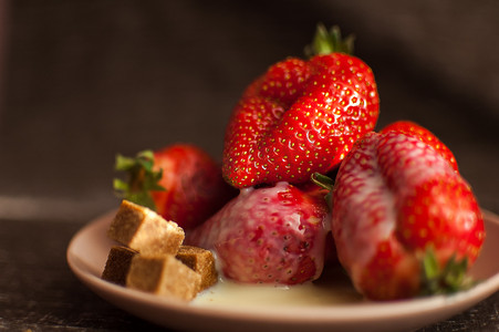 圆盘上的红熟草莓，几块蔗糖和融化的白巧克力
