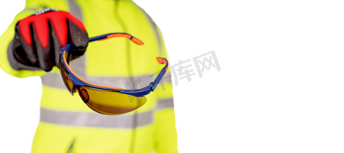 一名身穿亮黄色 hi-viz 外套和红色安全手套的建筑工人为观众戴上有色安全眼镜，以保护在白色背景下隔离的眼睛。