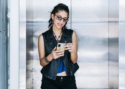 迷人的女孩在电梯门口用手机，一个人在电梯里发短信，城市女孩特写看她的手机