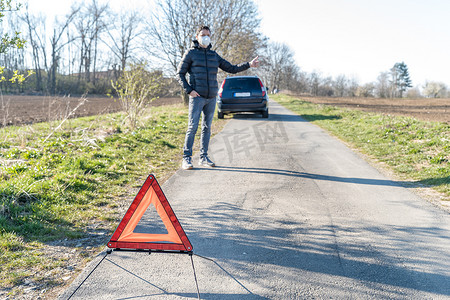 道路上一辆破损汽车前的红色警示三角。