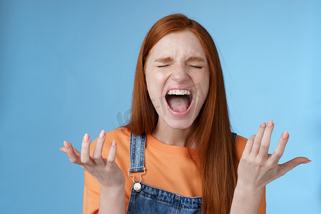 生气愤怒的喜怒无常的红发女孩大喊抱怨愤怒站着烦恼大声尖叫闭上眼睛大声喊叫向侧面举起双手沮丧完全难以置信感到被欺骗痛苦的背叛