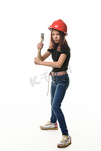 一个戴着安全帽的女孩正准备用白色背景中突显的锤子敲击