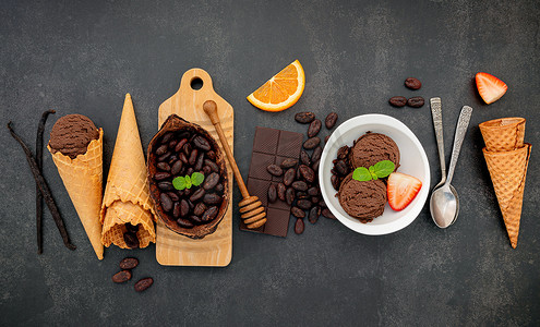 碗中的巧克力冰淇淋口味，黑巧克力和可可粒设置在深色石头背景上。