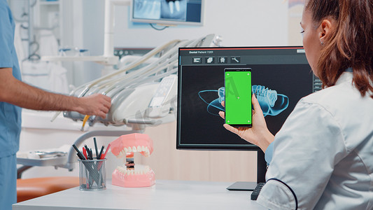 垂直拿着有绿色屏幕的智能手机的牙医