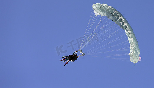 蓝天白云免费下摄影照片_一位跳伞者带着白色的降落伞，在蓝天白云的衬托下，特写。