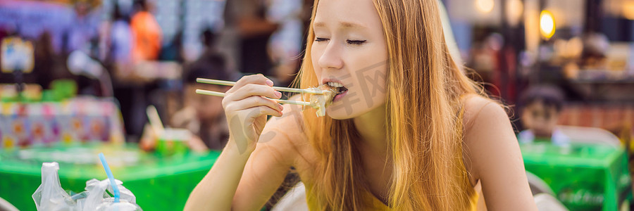 食品banner摄影照片_快乐可爱的女孩吃街头食品，在传统的小集市上看起来很愉快 BANNER，LONG FORMAT