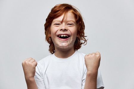 快乐的红发男孩用双手微笑着童年的快乐