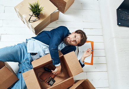一个拿着箱子的男人躺在办公室搬家的地板上拆包