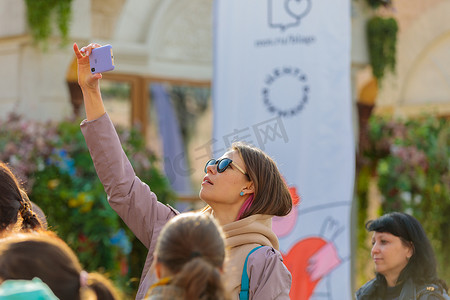 在一个城市节日上，一个女孩从高处用手机在头顶拍摄舞台。俄罗斯泽列诺格勒 2022 年 4 月 23 日