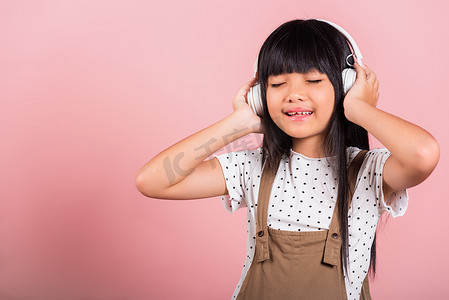 10 岁的亚洲小孩戴着无线耳机微笑着听音乐