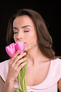 美丽的年轻女子闭着眼睛闻着粉色郁金香的黑色国际妇女节概念
