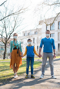 在冠状病毒紧急情况下一家人在阳光下散步