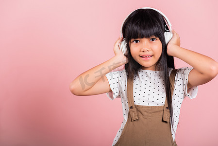 亚洲小孩 10 岁，头戴无线耳机，微笑着听音乐