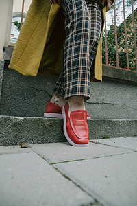 穿着红色鞋的女孩摄影照片_穿着格子裤和红鞋的女人的腿
