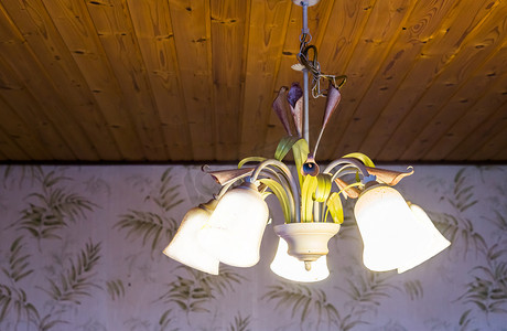 美丽的复古室内背景，木质天花板上挂着一盏点燃的复古吊灯，装饰着鲜花的灯，家居室内