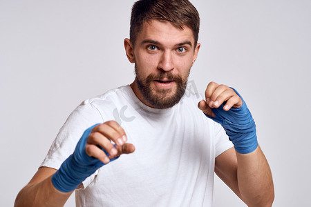 一个身穿白色 T 恤拳击绷带的运动型男子，手上缠着拳击练习，提高技能