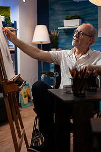 老年人在家庭艺术工作室的画架上画静物以进行业余爱好和娱乐