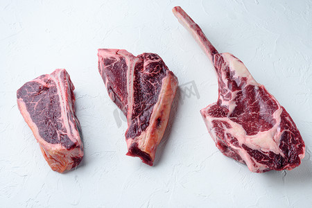 韭菜肉丁摄影照片_白石背景中的干熟生牛肉、战斧、丁字骨或牛排和俱乐部牛排