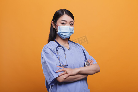 戴着听诊器和防护面罩的年轻成人保健诊所亚洲护士的画像。