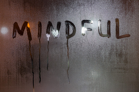 夜湿窗玻璃上写的“注意”一词，特写，背景模糊