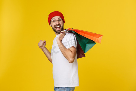 免费场摄影照片_留着胡子的男人，提着购物袋，在黄色的免费场地上感到快乐