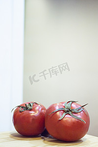 吐鲁番西红柿摄影照片_木切板上两个红熟的西红柿
