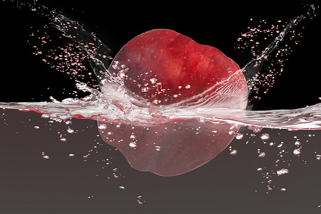 红苹果落入水中，黑色 backg 上有飞溅隔离
