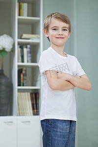 在家中双臂交叉站立的休闲服小男孩的肖像