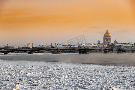 日落时圣彼得堡的冬季全景，以撒大教堂和 Blagoveshenskiy 桥为背景，冰冻的涅瓦河上的蒸汽，橙色的天空