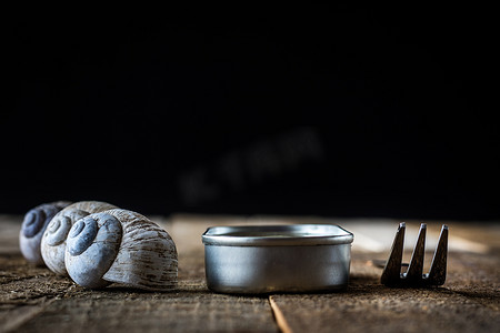 木制旧桌上的蜗牛壳和锡罐