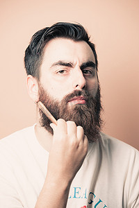留胡子的帅哥剃胡子，年轻的白种人留胡子的男人在隔离期间在家里修剪胡须。