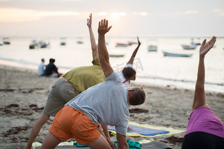 鸽子大海摄影照片_毛里求斯印度洋空荡荡的海滩上，妇女们在做瑜伽练习或支撑鸽子姿势。