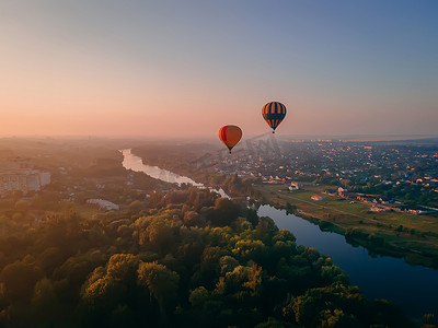夏日日出时，两个彩色气球飞越欧洲小城市的绿色公园和河流