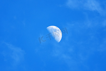 圆月光摄影照片_万里无云的蓝色天空中的月亮。