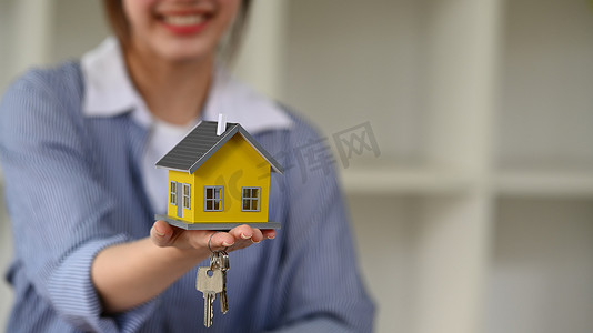微笑的女性财务顾问手拿着房子模型和钥匙。