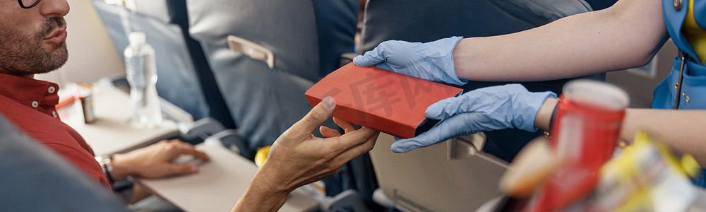 男性乘客从机上提供食物的女空姐手中接过饭盒的特写镜头