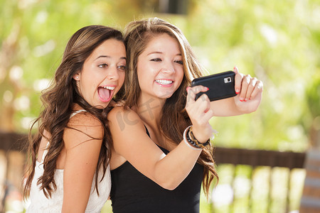 两个漂亮的混血女友用智能手机在户外自拍