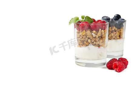Muesli 甜点用酸奶和蓝莓在玻璃中在白色背景。