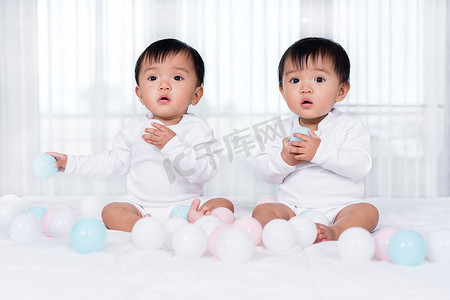 快乐的双胞胎婴儿在床上玩彩球