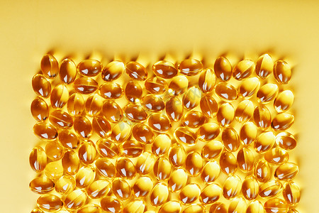 液体鱼油摄影照片_黄色背景上装有液体维生素 D3 的壳中的胶囊和文字位置