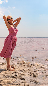 夏日，在蓝云红湖的背景下，穿着漂亮裙子的快乐女孩，外表魅力十足