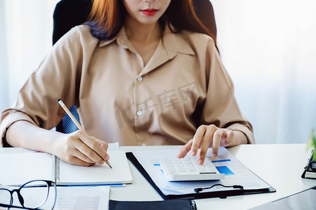 财务和投资审计概念，女审计员正在按计算器通过文书工作检查公司利润的预算和正确性以计算年税。