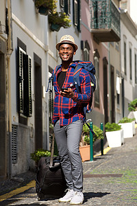 全长快乐的非洲裔美国旅行人背着包和手机走在街上