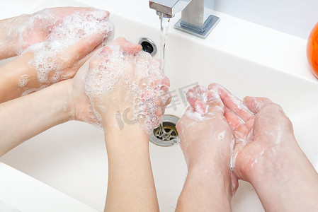 孩子们在起重机下用肥皂用水洗手。
