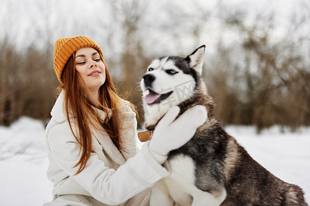 快乐的女人在雪地里和狗玩耍有趣的友谊生活方式
