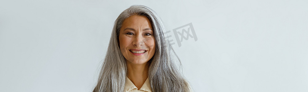 灰白的头发摄影照片_灰色背景下头发灰白、双臂交叉、面带微笑的亚洲女性肖像