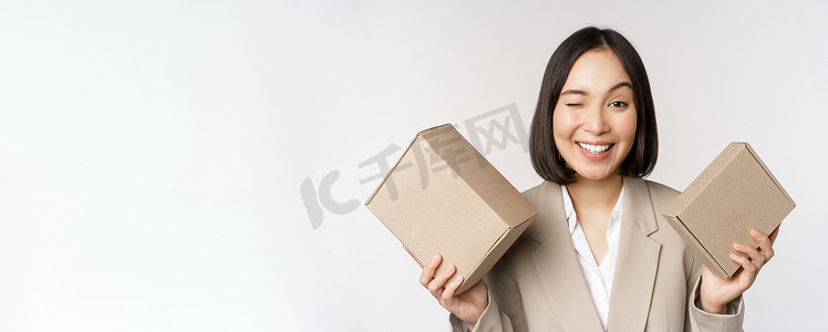 女售货员的形象，亚洲女商人拿着装有公司品牌产品的盒子，对着镜头微笑，站在白色背景下