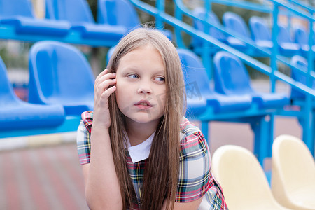 学校体育场蓝黄相间的看台上穿着校服的漂亮女孩。