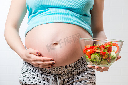 孕妇的肚子和一碗蔬菜沙拉特写