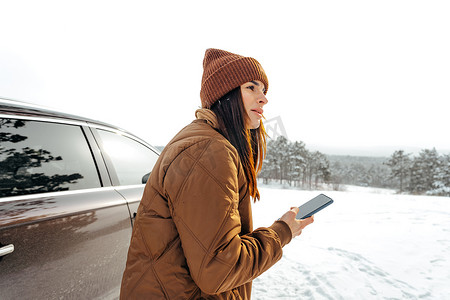 穿着冬季保暖夹克的女人在多雪的冬季森林里行走